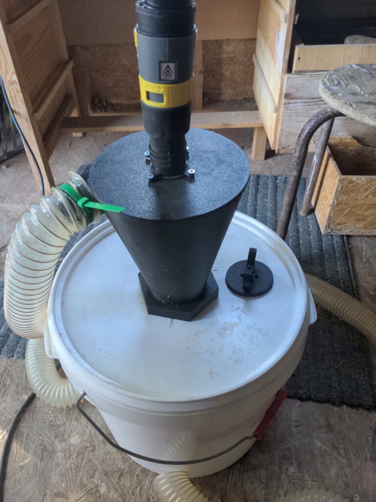 Séparateur cyclonique noir installé sur un seau blanc et raccordé à l’aspiration de l’atelier