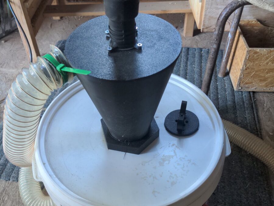 Séparateur cyclonique noir installé sur un seau blanc et raccordé à l’aspiration de l’atelier
